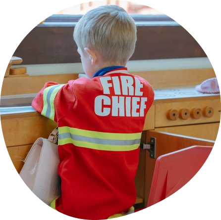 Child dressed as fire chief at Playful Scholars preschool in Midland, MI, where learning feels like play.