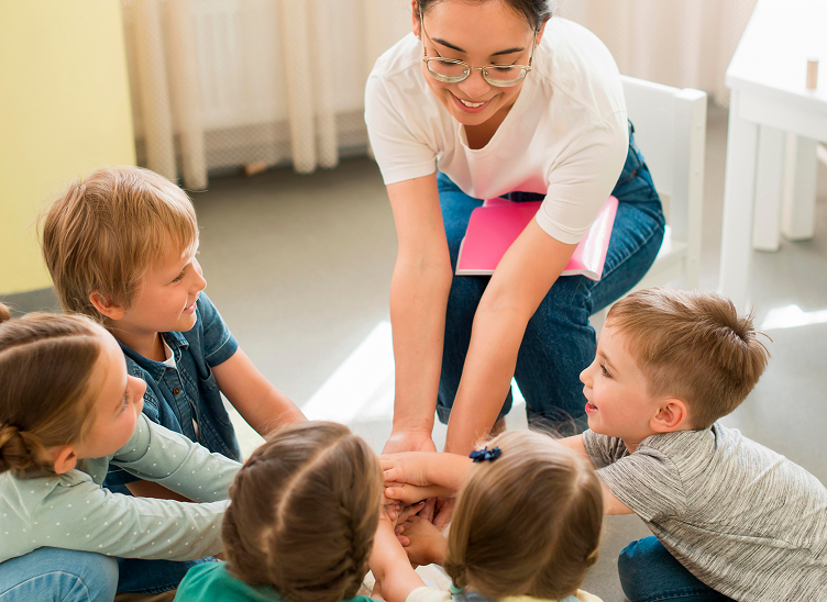 Teacher and children joining hands at a Midland MI preschool, promoting growth and collaboration.