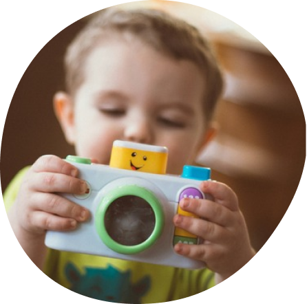 Infant playing with a toy camera at Playful Scholars, Midland MI, gentle learning environment.