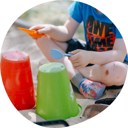 Child engaging in creative play at Midland, using cups as drums outdoors.