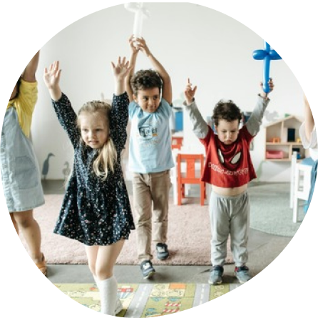 Preschool children at Playful Scholars in Midland, MI enjoying creative play and learning with raised hands.